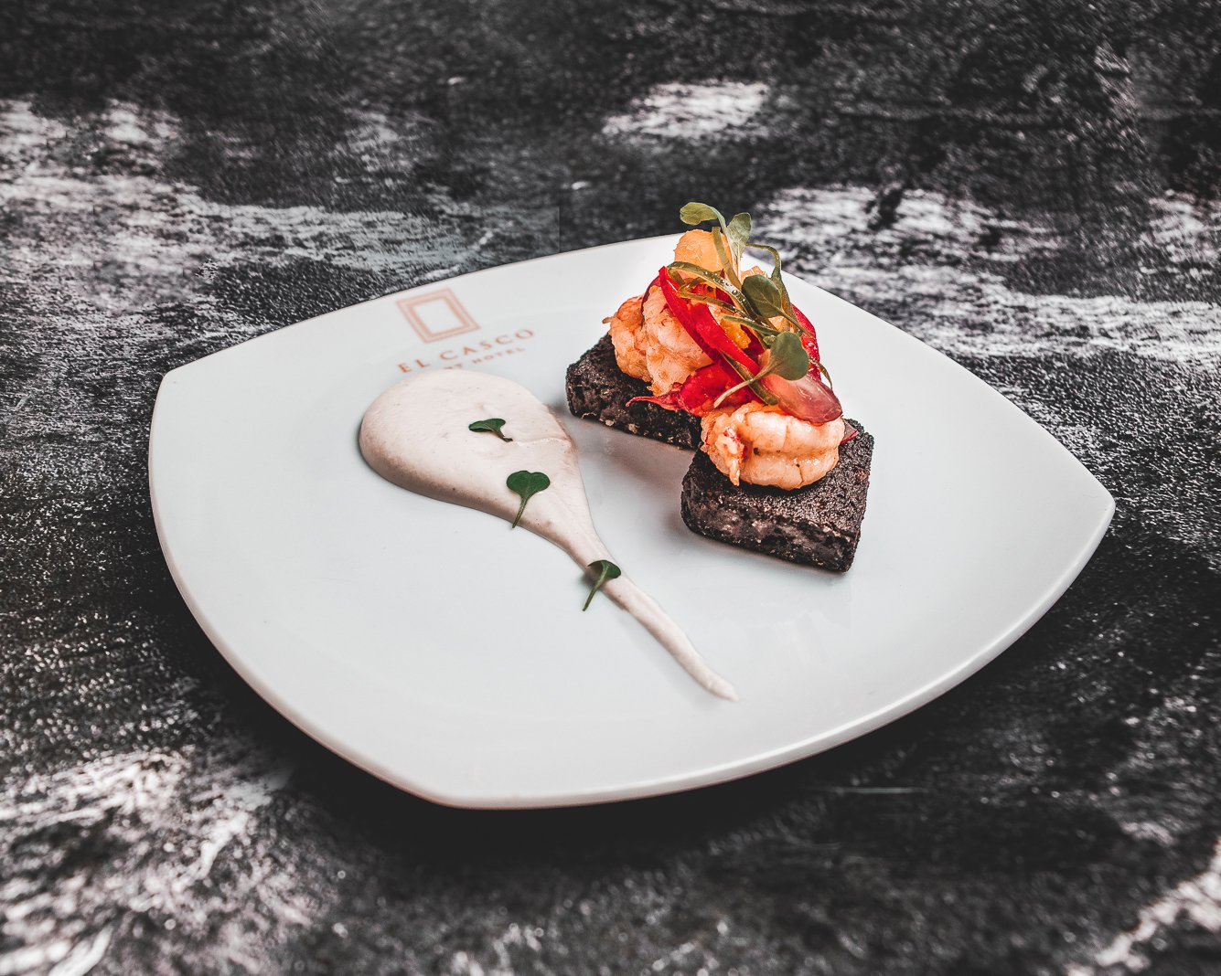 Langostinos en manteca de cajún, cake de morcilla y ajo blanco